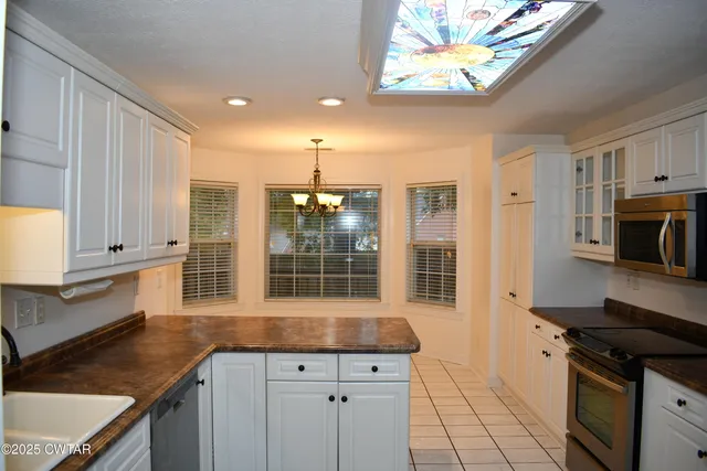 a kitchen with granite countertop white cabinets and stainless steel appliances