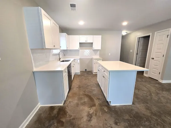 a large white kitchen with kitchen island a sink stainless steel appliances and cabinets