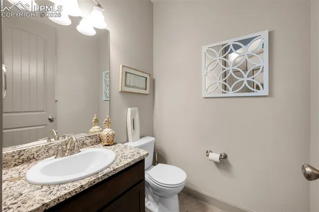 a bathroom with a granite countertop toilet a sink and mirror