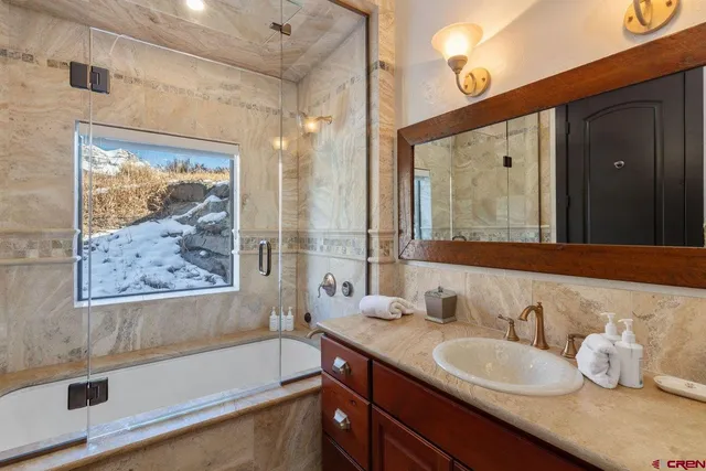 a bathroom with a granite countertop tub sink and mirror