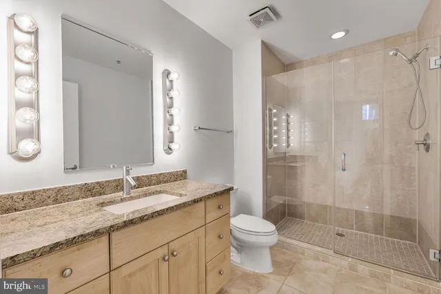a bathroom with a granite countertop sink a toilet and shower