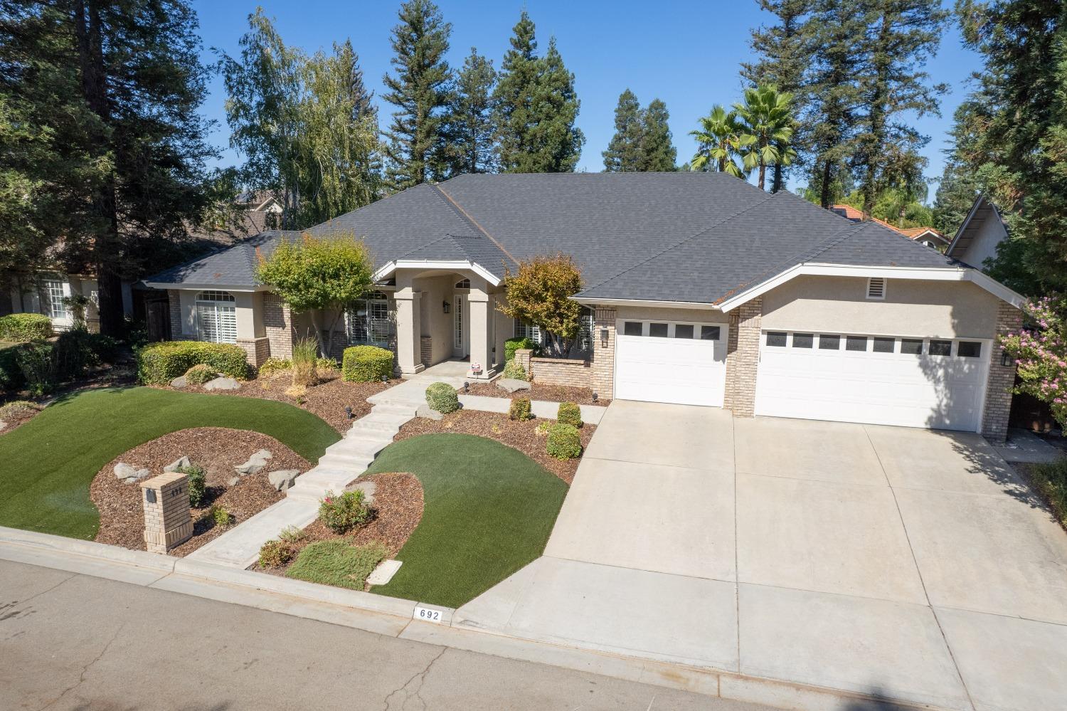 692 East Blue Ridge Road Fresno, CA 93725 - Photo 2 of 68 a view of a white house with a yard plants and large tree