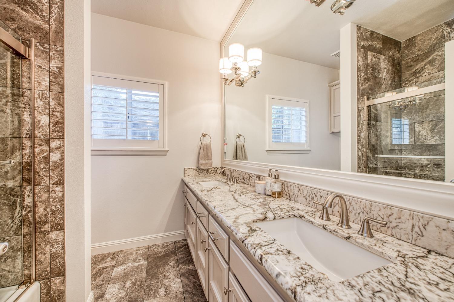 692 East Blue Ridge Road Fresno, CA 93725 - Photo 34 of 68 a bathroom with a granite countertop tub a sink and a large mirror