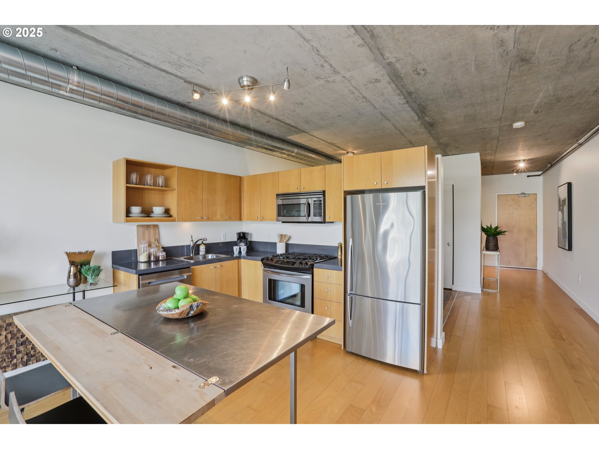 1926 West Burnside Street, Unit 912 Portland, OR 97209 - Photo 11 of 19 a kitchen with stainless steel appliances granite countertop a refrigerator a stove and a sink with wooden floor