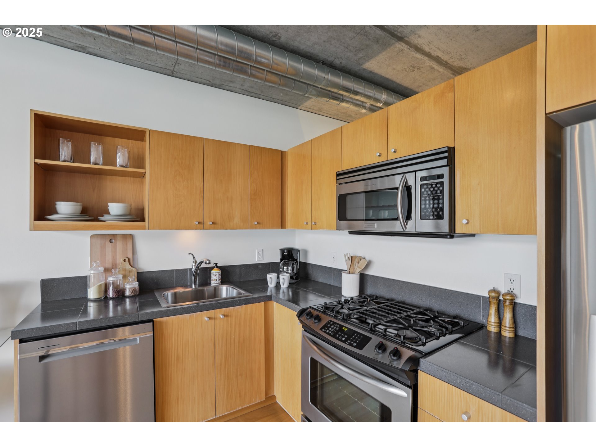 1926 West Burnside Street, Unit 912 Portland, OR 97209 - Photo 10 of 19 a kitchen with stainless steel appliances stove top oven and cabinets