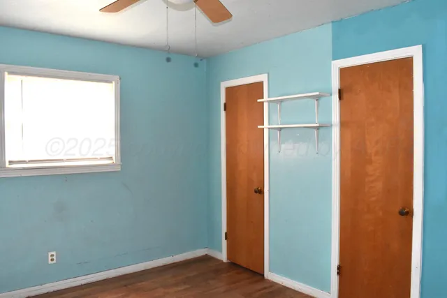 an empty room with wooden floor closet and windows