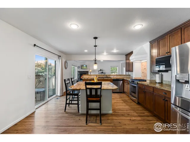 a dining hall with stainless steel appliances kitchen island granite countertop a table chairs and a refrigerator