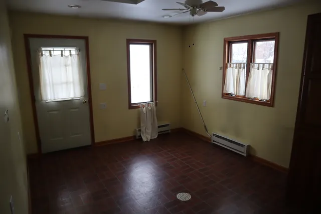 an empty room with wooden floor and windows