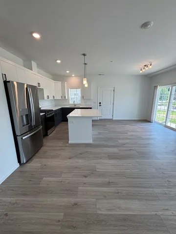 a large kitchen with a refrigerator a stove a microwave and white cabinets