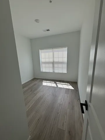 an empty room with wooden floor and windows