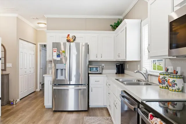 a kitchen with stainless steel appliances a refrigerator sink and white cabinets