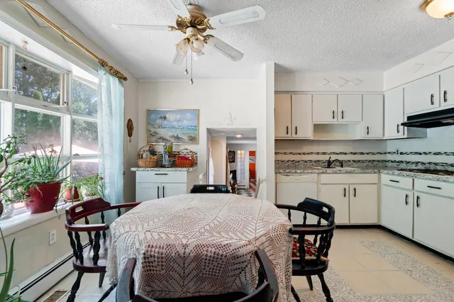 a kitchen with stainless steel appliances kitchen island granite countertop a table chairs sink and cabinets