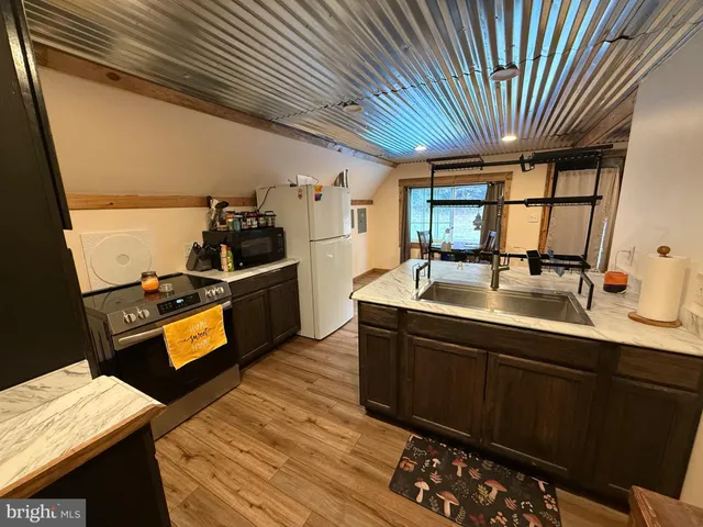 a kitchen with stainless steel appliances kitchen island granite countertop a table chairs and a refrigerator