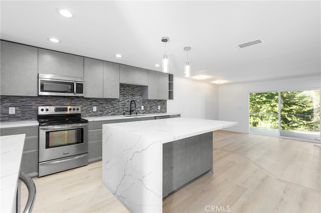 a kitchen with stainless steel appliances kitchen island granite countertop a stove a sink and a microwave