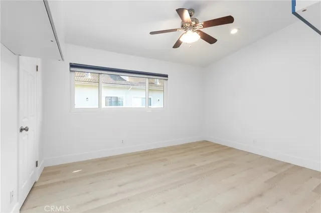 an empty room with chandelier fan and windows