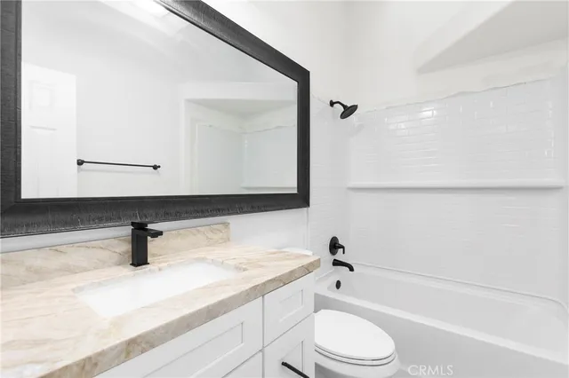a bathroom with a bathtub sink vanity mirror and toilet