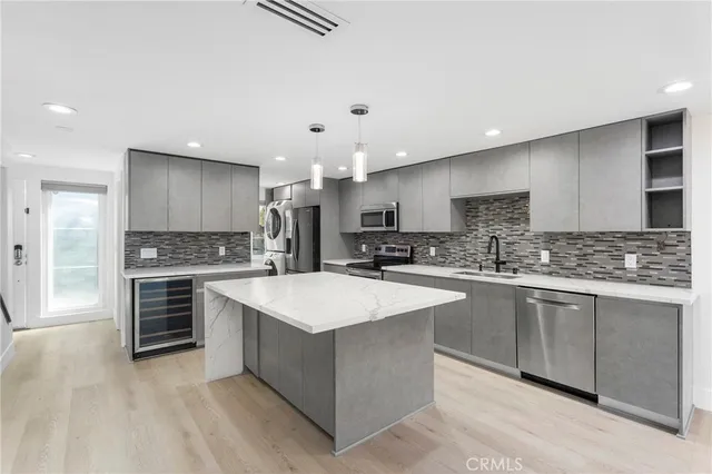 a large kitchen with stainless steel appliances a sink dishwasher stove and white cabinets with wooden floor
