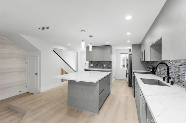 a large kitchen with stainless steel appliances kitchen island granite countertop a sink and a stove top oven with wooden floor