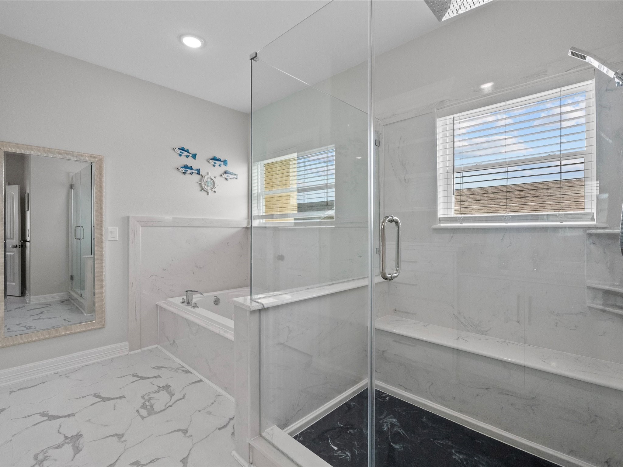 1018 Seashell Drive Surfside Beach, TX 77541 - Photo 44 of 49 This modern bathroom features marble-style tiles, a glass-enclosed shower, a built-in bathtub, and a large mirror. Natural light streams through a window with blinds, adding a bright and welcoming touch.