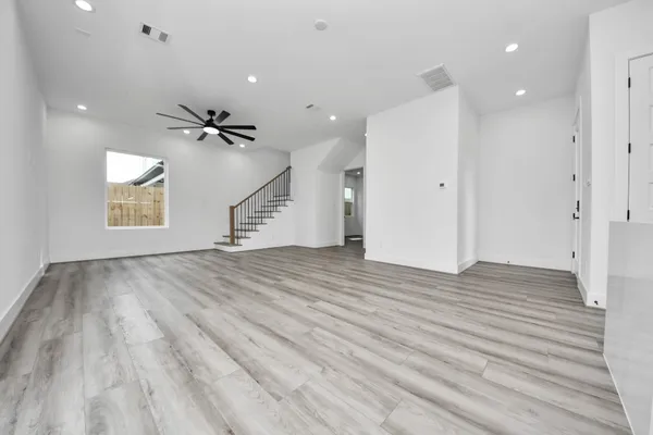 a view of empty room with wooden floor and fan