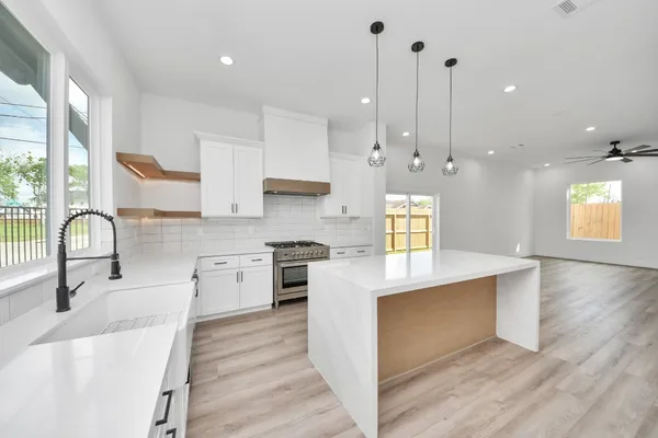 a kitchen with kitchen island granite countertop a stove a sink a center island and a window