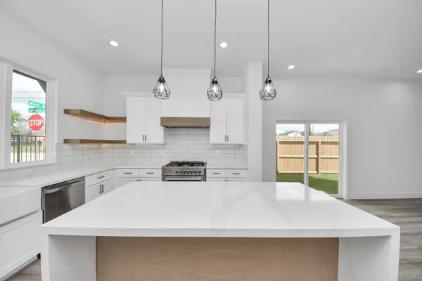 a kitchen with kitchen island a sink a stove a refrigerator and a window