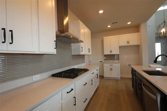 a kitchen with stainless steel appliances granite countertop a stove a sink and a refrigerator with white cabinets
