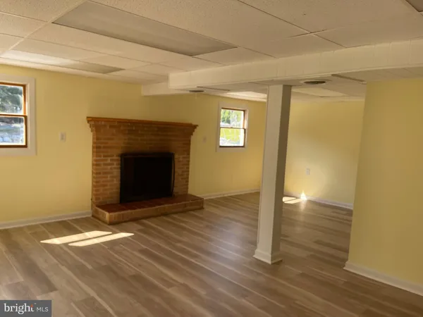 a view of empty room with wooden floor and a fireplace