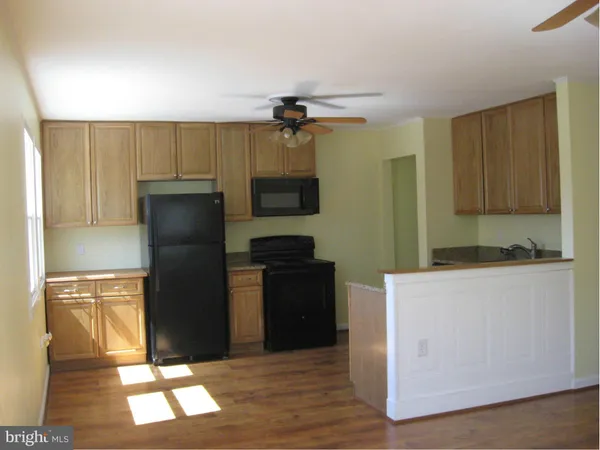 a kitchen with a refrigerator a stove top oven a counter space and wooden floor