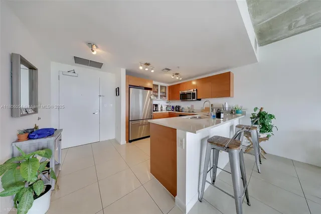 a kitchen with stainless steel appliances kitchen island granite countertop a refrigerator and a sink
