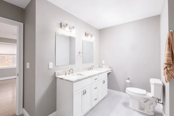 a bathroom with a granite countertop toilet a sink and a mirror
