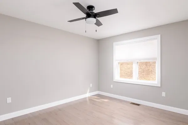 an empty room with a window and a ceiling fan