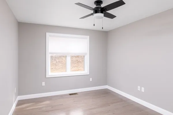 an empty room with a window and a fan