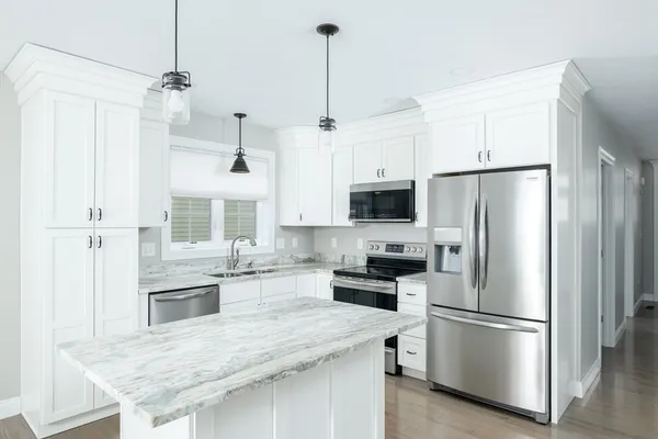 a kitchen with stainless steel appliances granite countertop a refrigerator a stove a sink and white cabinets