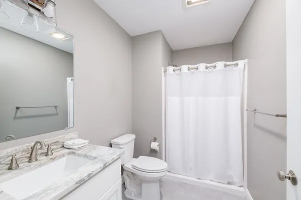 a bathroom with a granite countertop sink toilet and a mirror