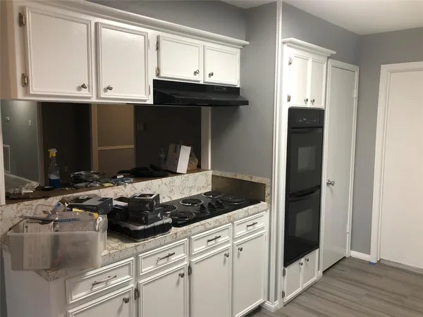 a kitchen with granite countertop white cabinets and black appliances