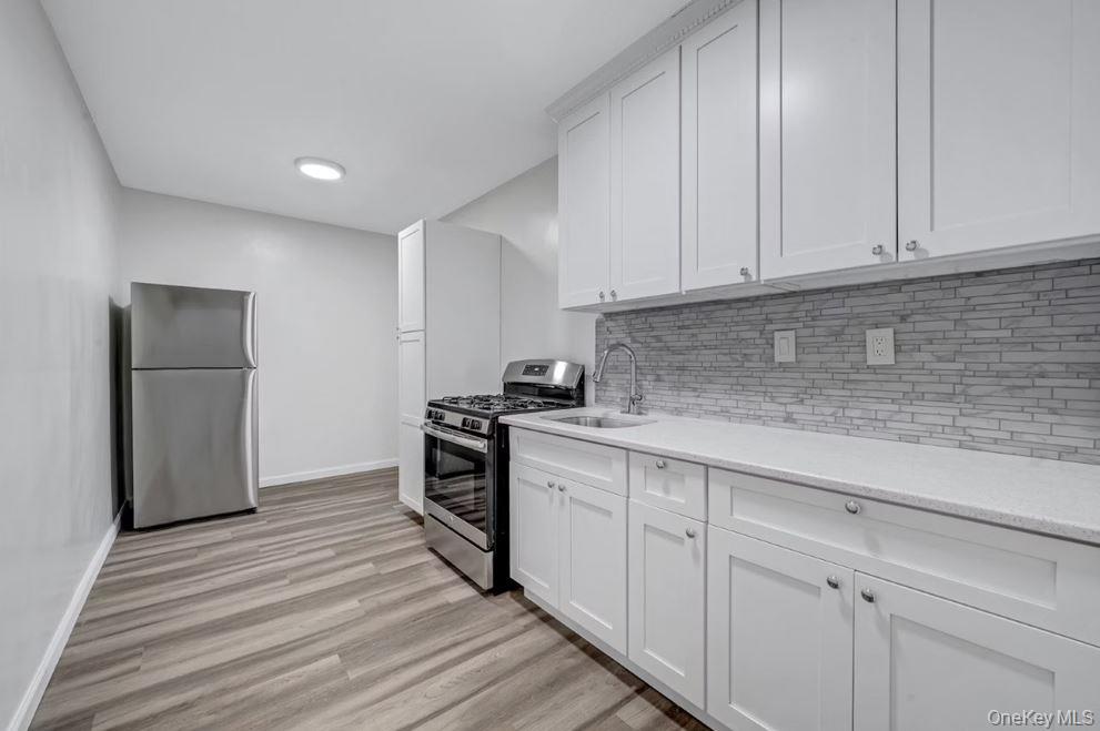 609 Palmer Road, Unit 3M Yonkers, NY 10701 - Photo 13 of 18 Kitchen with appliances with stainless steel finishes, light wood-style flooring, backsplash, and white shaker cabinets