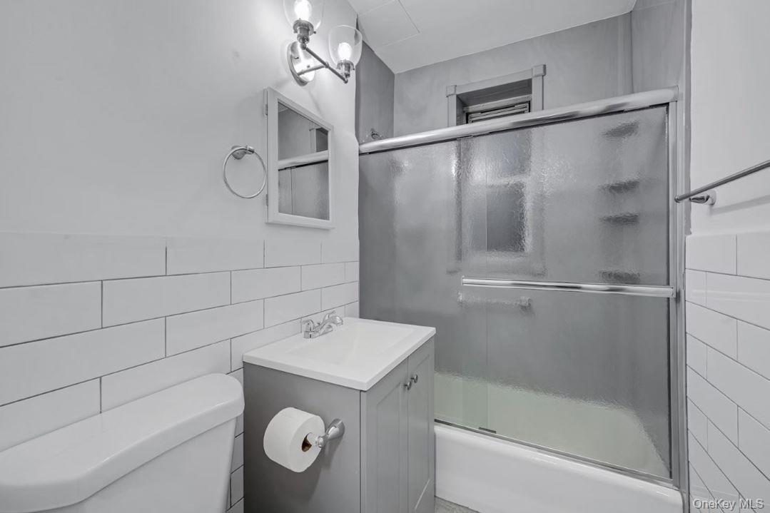 609 Palmer Road, Unit 3M Yonkers, NY 10701 - Photo 17 of 18 Bathroom featuring shower / bath combination with glass door, vanity, and subway tile walls