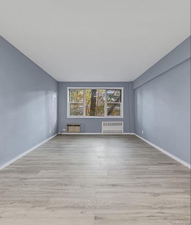609 Palmer Road, Unit 3M Yonkers, NY 10701 - Photo 7 of 18 Another view of the living room area with light wood-style floors, wall A/C, and radiator