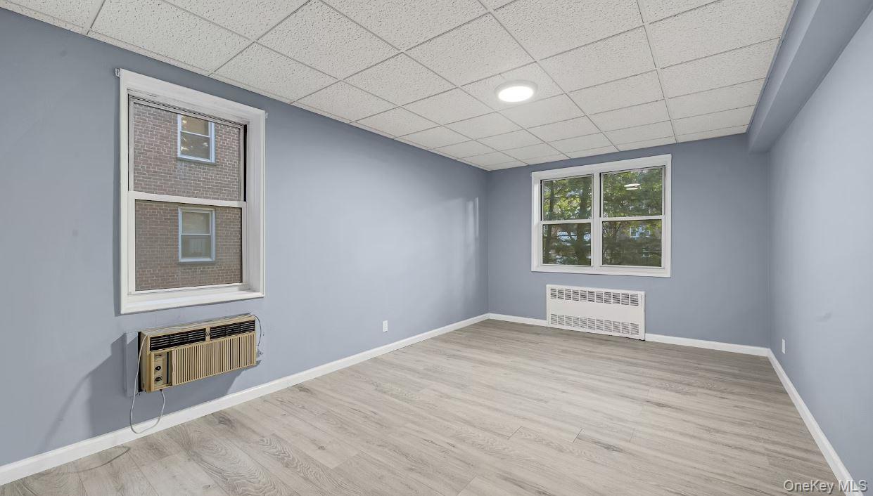 609 Palmer Road, Unit 3M Yonkers, NY 10701 - Photo 10 of 18 Bedroom featuring two windows, wood finished floors, radiator heating unit, a drop ceiling, and a wall unit AC