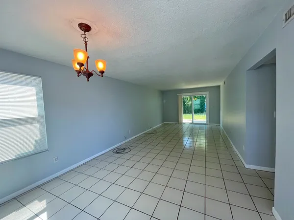 a view of an empty room and window and chandelier fan
