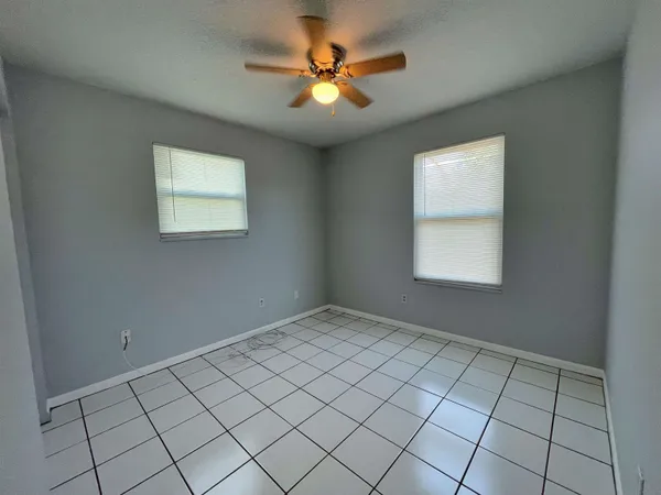 an empty room with windows and ceiling fan