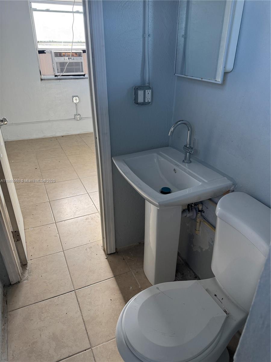 354 Rardin Avenue, Unit 12 Pahokee, FL 33476 - Photo 5 of 11 a bathroom with a toilet a sink and mirror
