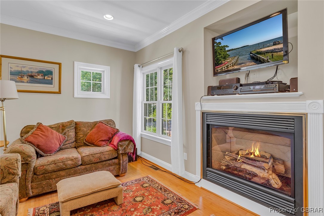 189 Virginia Road Reedville, VA 22539 - Photo 8 of 46 Living room with wood finished floors, crown molding, a glass covered fireplace, baseboards, and recessed lighting