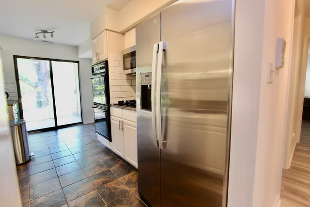 a kitchen with a refrigerator and white cabinets
