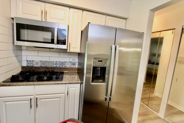 a kitchen with stainless steel appliances granite countertop a refrigerator and a microwave