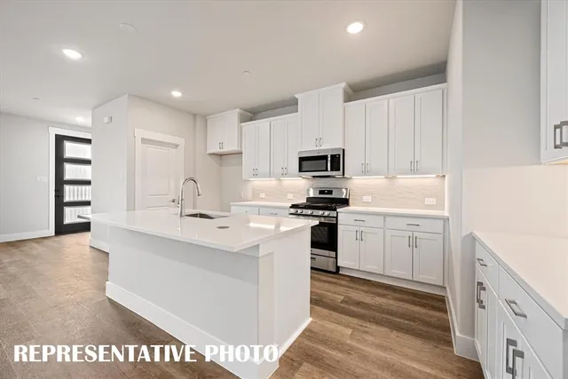 a kitchen with kitchen island a sink a stove a refrigerator cabinets and a center island