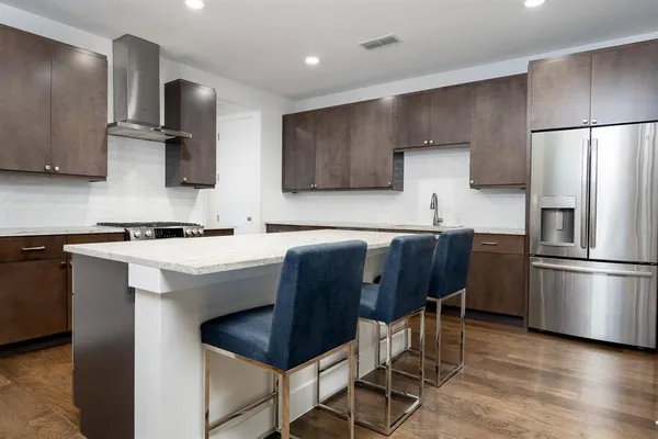 a kitchen with stainless steel appliances a refrigerator a sink a stove a microwave and wooden cabinets