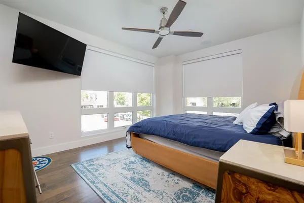 a bedroom with a bed a flat screen tv and a window