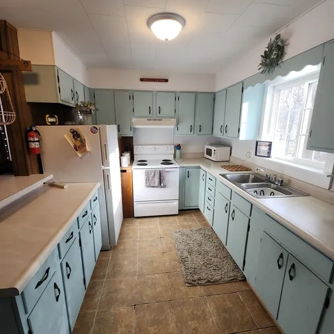 a kitchen with a sink a stove top oven a refrigerator and white cabinets